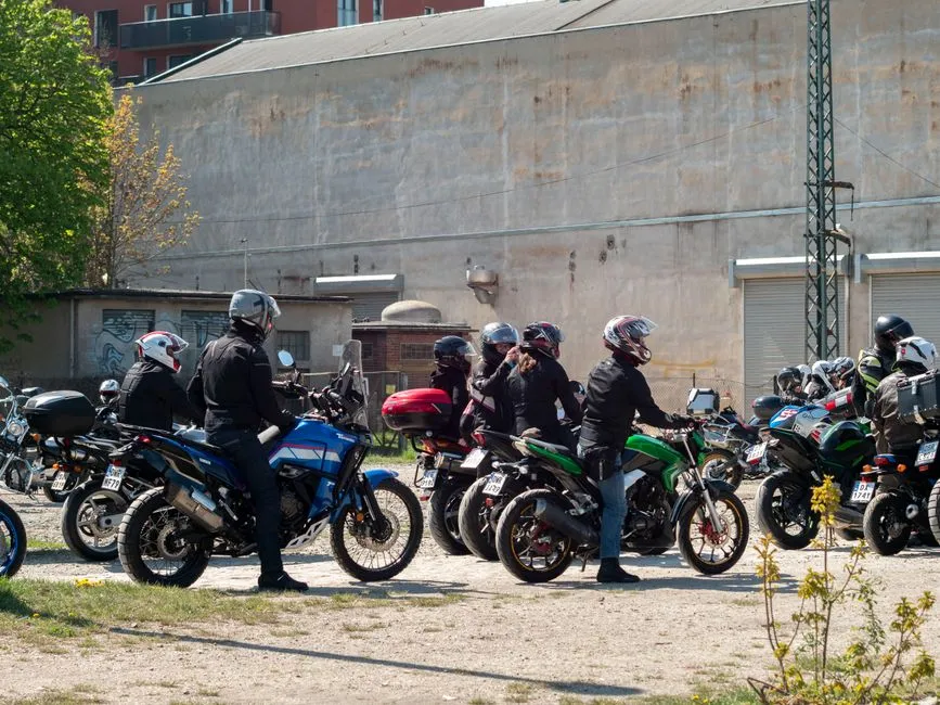 Jeune motard assis sur une moto légère, casque à la main, dans une rue ensoleillée