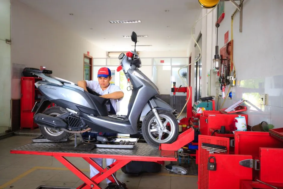 Moto routière sur béquille d'atelier pendant une révision, mécanicien vérifiant le niveau d'huile moteur